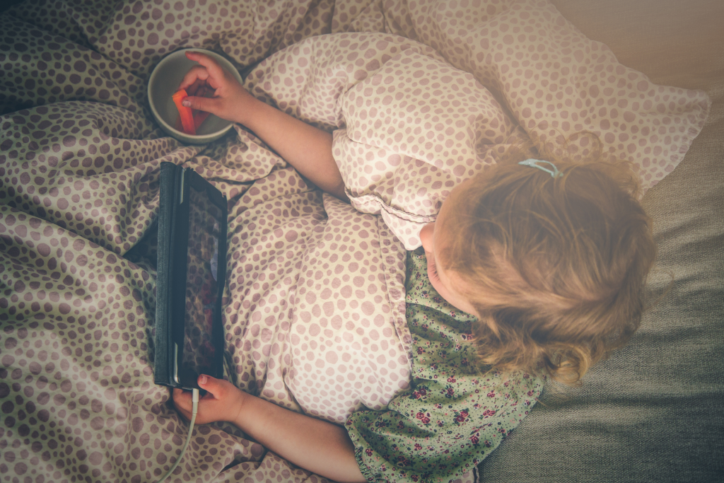 child in bed with ipad showing the screen time myth that parental controls work